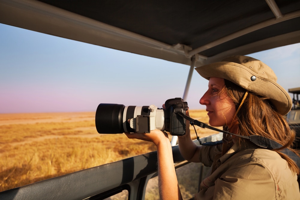 Femme prenant des photos depuis une jeep de safari
